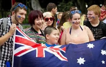 Grupo de personas de diferentes culturas al aire libre cada uno tomando por un extremo la bandera de Australia en día soleado