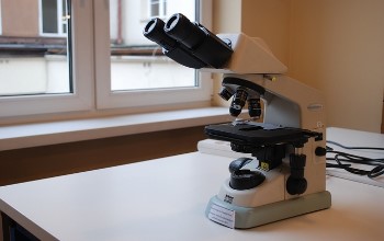 Microscopio de color negro y blanco sobre una mesa blanca en un laboratorio