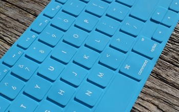 Teclado flexible de color azul claro con las letras blancas sobre una mesa de madera