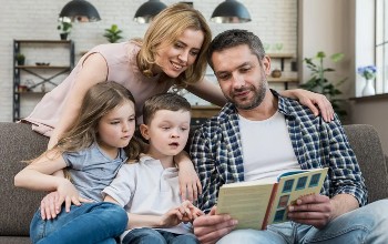 Foto de una familia, mamá, papá, niño y niña, leyendo un libro juntos