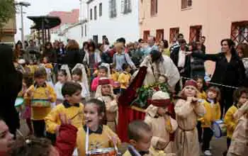 Grupo de niños cargando figura de virgen pequeña en procesión
