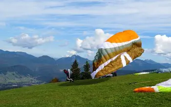 Persona corriendo sobre colina para saltar en parapente en dia soleado