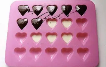 molde para hacer bombones en formas de corazón con una parte llena de chocolate derretido