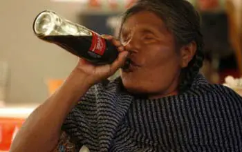 Mujer indígena sentada tomando una bebida gaseosa