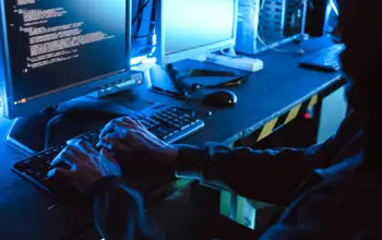 Hacker escribiendo en una computadora en la oscuridad