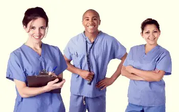 Grupo de enfermeros parados vestidos de azul sonriendo en un fondo blanco