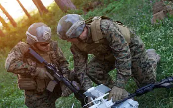 Dos soldados uniformados usando dron para explorar en un bosque