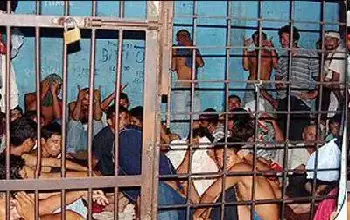 Grupo grande de hombres encarcelados  dentro de una celda muy pequeña sin espacio