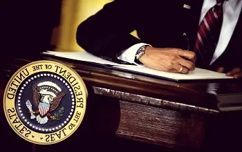 la mano de una persona firmando un documento en un podio que dice presidente de los estados unidos