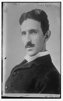 Persona observando la resolución de una foto, frente a una laptopFotografía antigua en blanco y negro de Nikola Tesla cuando era joven