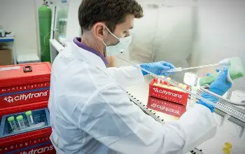 Hombre científico  con mascarilla analizando productos químicos en un laboratorio