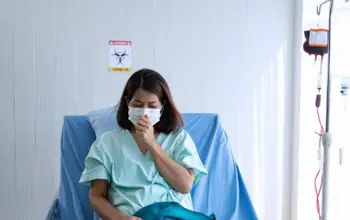 Mujer en una camilla de hospital, con tapabocas y al parecer le realizan una infusión de sangre