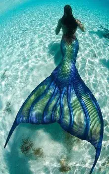 Mujer con disfraz de sirena cola verde brillante con azul nadando bajo el agua de espalda