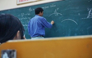 Profesor realizando una demostración matemática sobre un pizarrón verde en un salón de clases