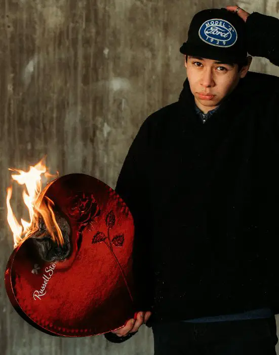 Hombre triste vestido de color negro con un corazón rojo en su mano quemándose sobre un fondo marrón y gris