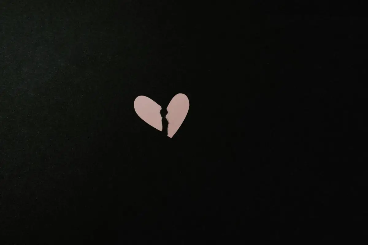 Corazón rosado pequeño, roto sobre un fondo de color negro