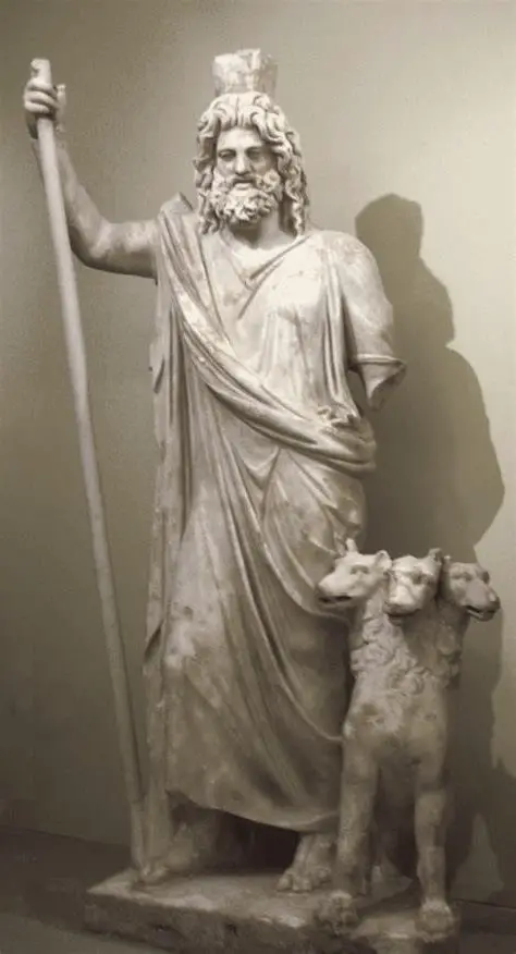 Estatua de Hades de pie con un bastón y acompañado de un perro de tres cabezas.