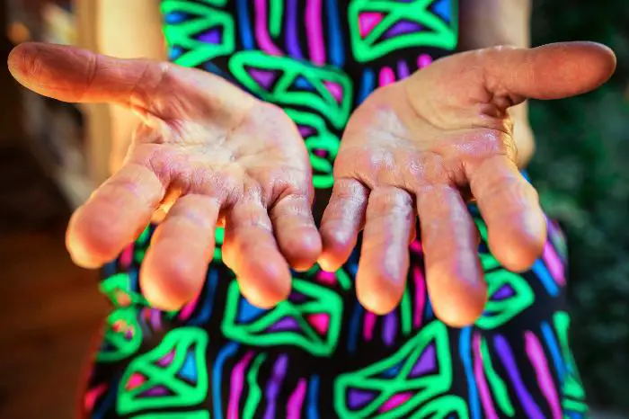 Imagen de un par de manos de una persona extendidas en un fondo borroso de colores