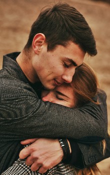 Hombre y mujer abrazándose con los ojos cerrados en un fondo borroso